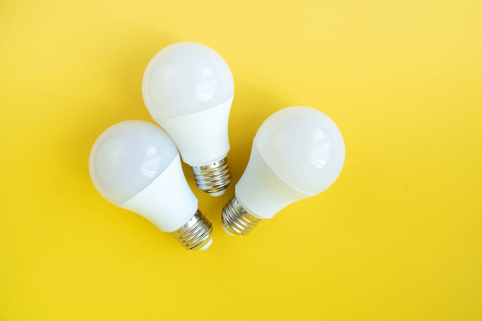 Three LED light bulbs on yellow background. energy saving concept.