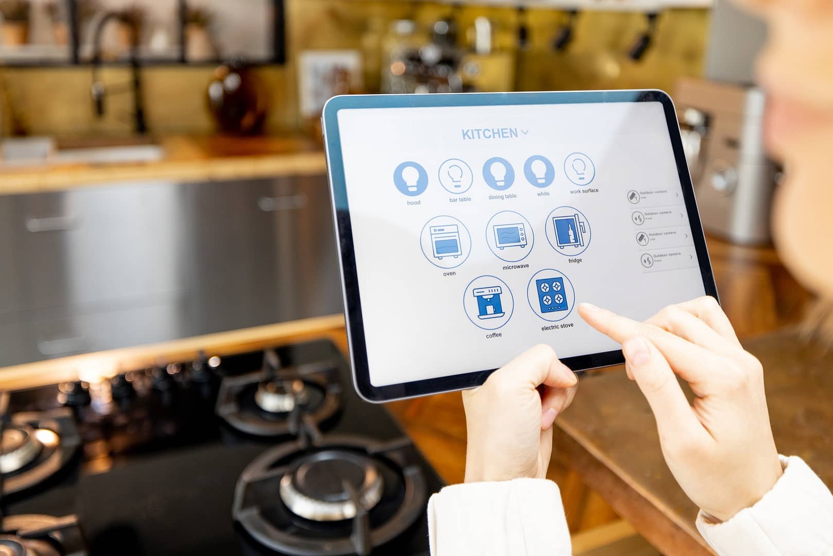 Woman holding digital tablet with running smart home application in the kitchen