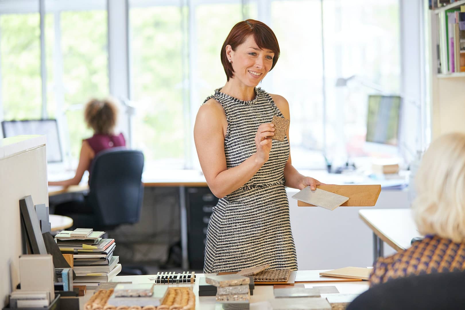 Female interior designer showing swatches to colleague in office