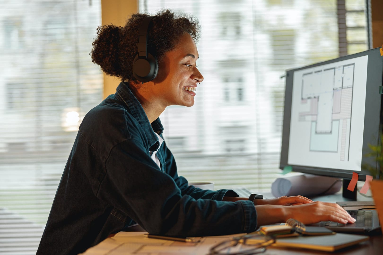 Smiling Afro american woman interior designer in headphones works in home office