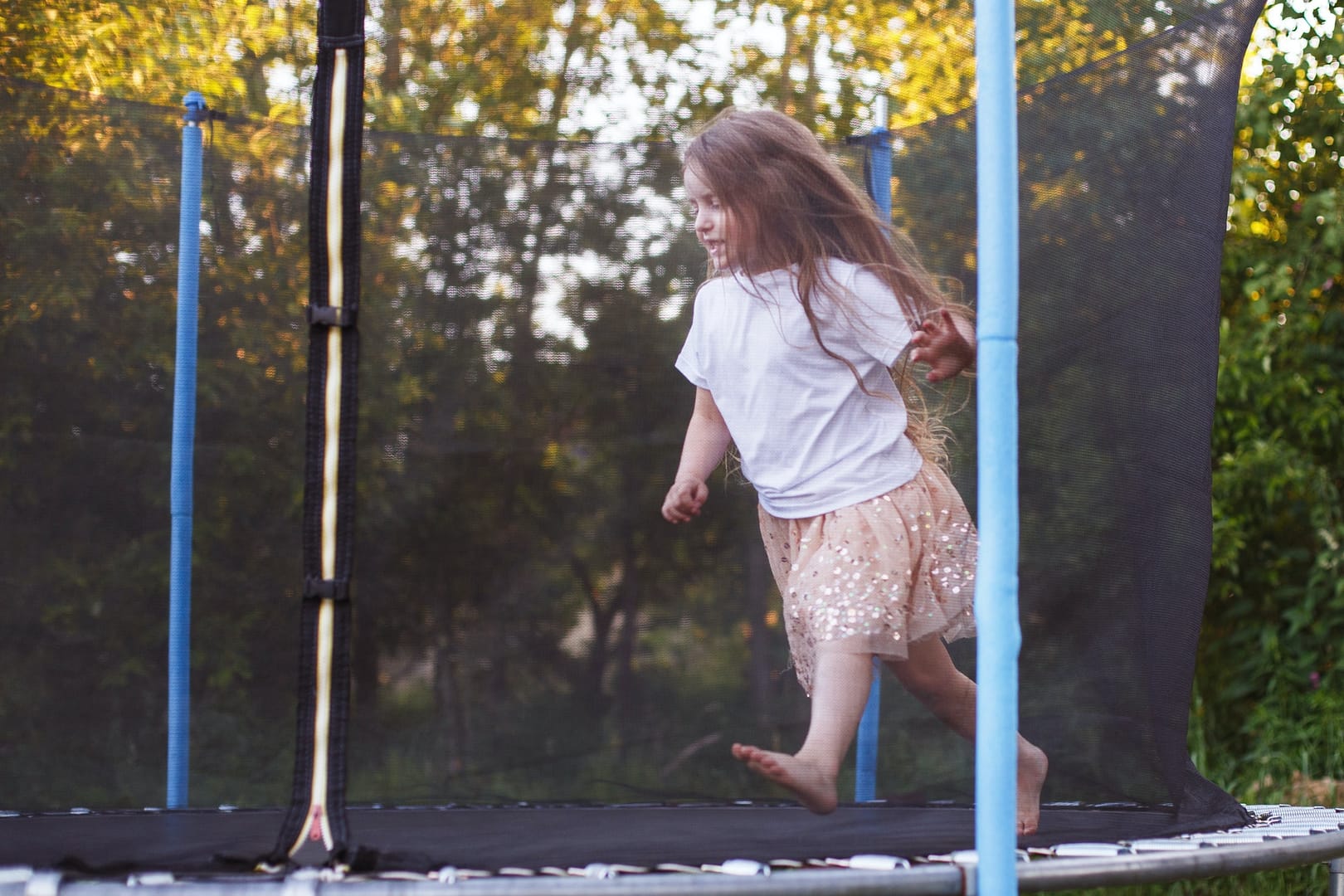 Little child girl jumping on the trampoline in the back yard