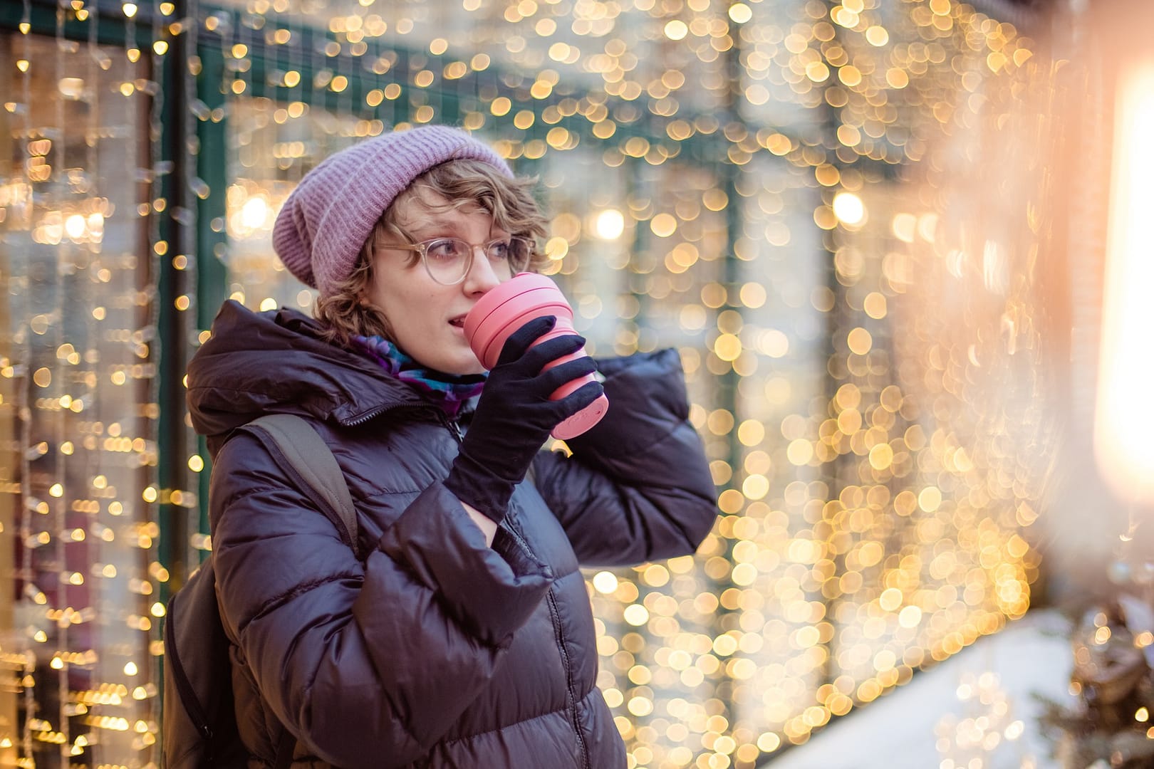 cheerful caucasian woman drinking coffee outdoors in chrisms light around. Eco friendly reusable cup