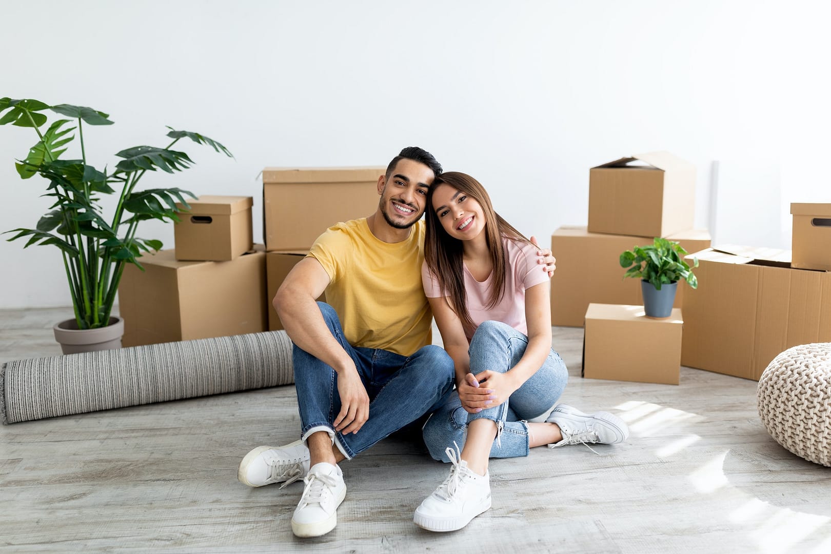 Relocation concept. Happy multiracial homeowners sitting on floor