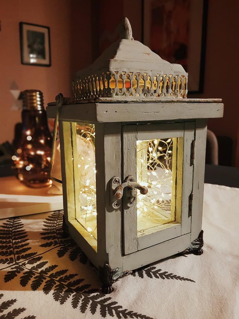 Close-up of rustic vintage lantern with string of led lights inside.